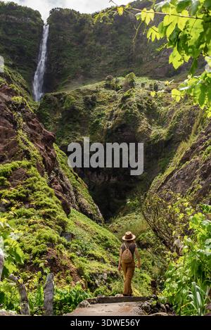 Eine Frau mit Rucksack und Hut erkundet die üppige und grüne Landschaft von Rocha do Navio in Madeira, Portugal, umgeben von lebhaftem Grün und Stockfoto
