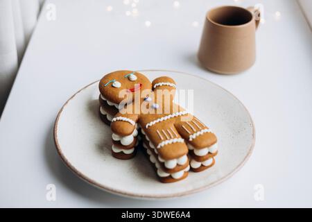 Dekorierter Lebkuchenmann-Kuchen auf einem Teller, perfekt für die Weihnachtszeit. Der Kuchen ist kreativ gestapelt und dekoriert, was den festlichen Urlaub einfängt Stockfoto