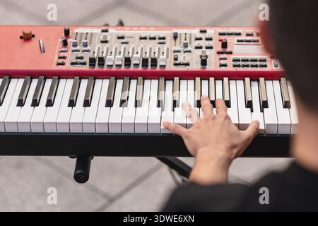 Die Hand eines Straßenmusikers spielt anmutig auf einem Keyboard während eines Open-Air-Konzerts. Die Nahaufnahme fängt die Intensität und Leidenschaft der Live-Street-Mu ein Stockfoto