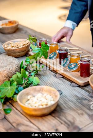 Eine elegante Präsentation mit verschiedenen Marmeladen, getrockneten Früchten und Nüssen auf einem rustikalen Tisch, perfekt für ein Gourmet-Erlebnis in gehobener Küche und kulinarischer Küche Stockfoto