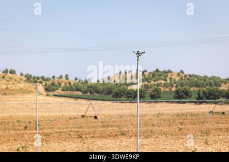 Sprinklerbewässerungsanlage in einem trockenen landwirtschaftlichen Feld in Castilla La Mancha, Spanien, wobei nachhaltige Wasserbewirtschaftungstechniken in ländlichen Gebieten hervorgehoben werden Stockfoto