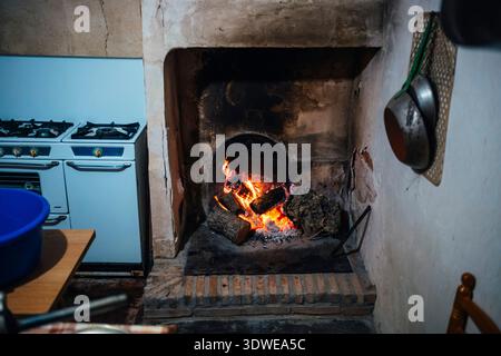 Eine rustikale Küchenszene mit einem Holzofen, der an traditionelle Methoden zur Zubereitung von Chorizo erinnert. Das Bild fängt die Wärme und Authentizität von ein Stockfoto