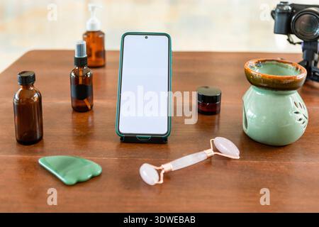 Ein ruhiges Zuhause, in dem Sie alles zur Selbstpflege finden, darunter natürliche Kosmetikprodukte, eine Gesichtsrolle, ein Smartphone und ein Aroma-Diffusor für einen Fass Stockfoto