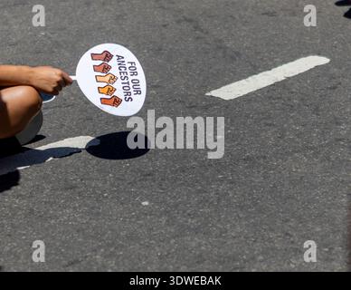 Eine Nahaufnahme der Hand einer Person, die ein Schild hält, das für unsere Vorfahren während eines Protests gegen indigene Rechte auf einer Straße der Stadt steht, das Einheit und Jus symbolisiert Stockfoto