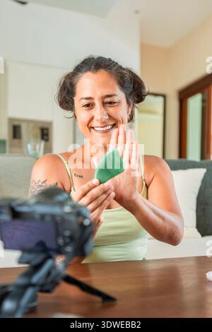 Content Creator demonstriert eine Routine zur Selbstpflege mit Hautpflegewerkzeugen in der häuslichen Umgebung. Ideal für Video-Tutorials zur Förderung von Entspannung und persönlichem Stockfoto