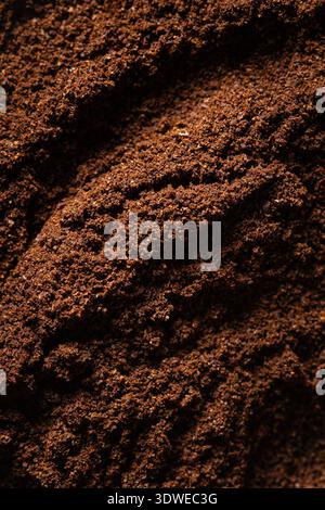 Eine detaillierte Nahaufnahme frisch gemahlener Kaffeebohnen mit kräftigen, strukturierten Mustern. Der dunkelbraune Farbton unterstreicht die Frische und den aromatischen Reiz von Stockfoto