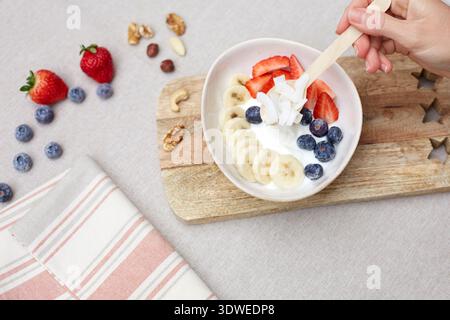 Eine köstliche Schüssel Joghurt mit frischen Bananenscheiben, Erdbeeren, Heidelbeeren und Kokosflocken. Diese nahrhafte Frühstücksoption ist perfec Stockfoto