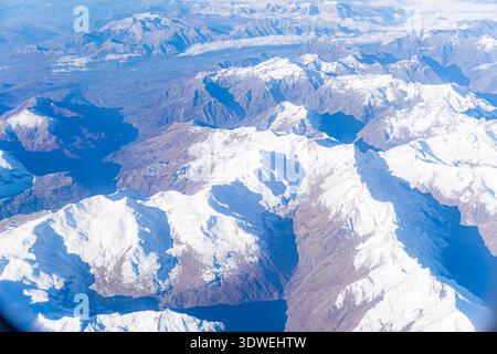 Aus der Vogelperspektive auf die majestätischen, schneebedeckten Alpen, die von einem Flugzeug aus aufgenommen wurden und die atemberaubende natürliche Schönheit und die weitläufige Bergkette darunter zeigen Stockfoto
