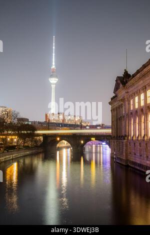 Ein atemberaubender Winterblick auf Berlin mit dem berühmten Fernsehturm und der Museumsinsel. Das Spiegelbild der Lichter der Stadt auf dem Fluss verstärkt die ruhige Atmosphäre Stockfoto