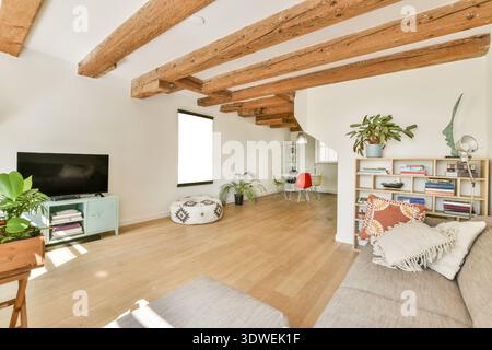Ein stilvolles Wohnzimmer mit Holzbalken, einem farbenfrohen Gemälde, einer üppigen Pflanze und modernen Möbeln. Der Raum strahlt Wärme und modernes Design aus Stockfoto