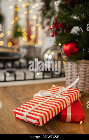 Gemütliches Ambiente mit einem geschmückten Weihnachtsbaum und Geschenktüchern auf einem Holztisch. Funkelnde Lichter und festliche Einrichtung sorgen für einen warmen, fröhlichen geldautomaten Stockfoto