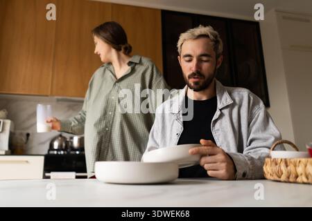 Ein Paar genießt ein ruhiges Frühstück zu Hause und teilt einen Moment der Liebe und Verbindung. Die Szene fängt die Wärme des Familienlebens mit einfachen Küchen ein Stockfoto