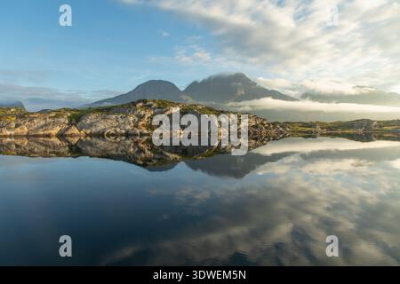 Die ruhige norwegische Szene zeigt kristallklares Wasser mit üppigen Landschaften und zerklüfteten Bergen und fängt die ruhige Schönheit der Lofoten fi ein Stockfoto