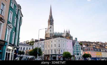 Ein atemberaubender Blick auf die St. Colman's Cathedral in Cobh, Irland, von den lebhaften, mehrfarbigen Häusern in den unteren Straßen der Stadt an einem ruhigen Tag aus gesehen. Stockfoto