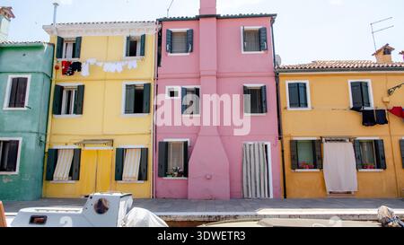 Lebhafte pastellfarbene Häuser säumen den Kanal auf der Insel Burano, Teil von Venedig, Italien. Diese bezaubernden Fassaden spiegeln sich im ruhigen Wasser der Veneta wider Stockfoto