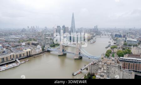 Eine atemberaubende Drohnenaufnahme von Londons berühmter Tower Bridge über die Themse. Das Foto fängt die pulsierende Stadtlandschaft und die architektonische Ele ein Stockfoto
