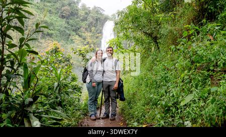 Ein Paar genießt eine malerische Wanderung durch üppiges Grün auf dem Weg zum Materuni Wasserfall in Tansania. Der Weg bietet wunderschöne Aussichten, eine lebendige Flora, eine Stockfoto