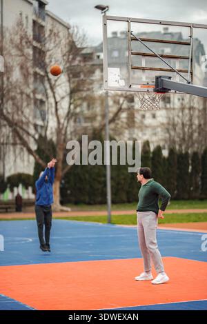Männer spielen Basketballspiel auf dem Platz im Freien Stockfoto