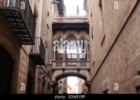 Eine kunstvoll verzierte gotische Brücke überspannt eine enge Gasse zwischen alten Steinhäusern im Herzen von Barcelonas historischem Viertel Stockfoto