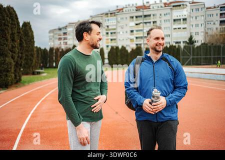 Zwei männliche Freunde reden auf der Laufbahn Stockfoto