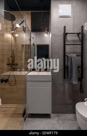 Ein modernes, gemütliches Badezimmer mit eleganten schwarzen Armaturen, Glasdusche und stilvoller Beleuchtung. Das minimalistische Design wird durch weiche, n Stockfoto