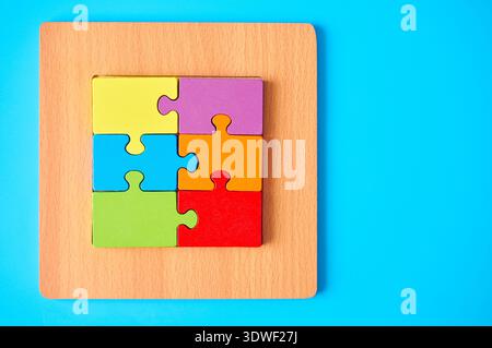 Ein buntes Puzzle auf einem Holzbrett symbolisiert Autismus und geistige Gesundheit und spiegelt die Komplexität und Vielfalt des autistischen Spektrums wider Stockfoto