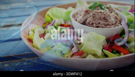 Mit flachem rosafarbenem Teller mit Salat, kleiner weißer Schüssel mit Thunfisch auf blauem Holztisch Stockfoto