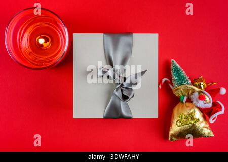 Ein Geschenk, eine Kerze des Weihnachtsmanns auf rotem Hintergrund. Weihnachtsdekoration. Stockfoto