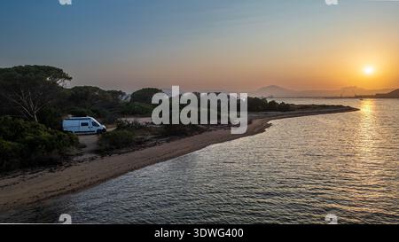 Eine eindrucksvolle Luftaufnahme des Lido del Faro in Olbia während der goldenen Stunde. Das Bild zeigt einen Wohnmobil, der entlang der wilden Küste geparkt ist Stockfoto