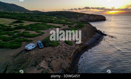 Hochwinkelansicht von zwei Wohnmobilen auf einer wilden Landzunge auf Capo Sperone, Insel Sant'Antioco, Sardinien, Italien. Das Bild erfasst den spiri Stockfoto