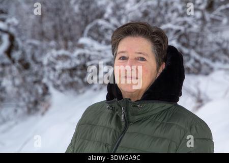 Frau, die in den verschneiten Bergen läuft und in die Kamera schaut Stockfoto