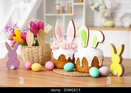 Osterkuchen mit Hasenohren und bemalten Eiern auf dem Tisch in der Küche Stockfoto