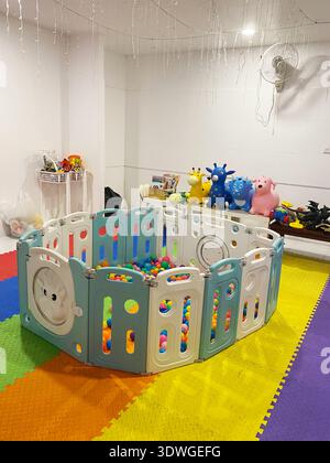 Spielbereich für Kinder in einem Café mit einem von einem Kunststoffzaun umgebenen Ballkasten, Plüschspielzeug und einem farbenfrohen Gummiboden für Sicherheit und Spaß Stockfoto
