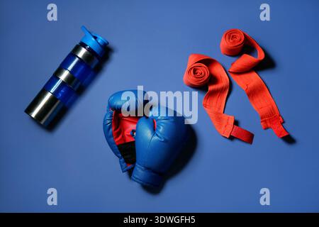 Boxhandschuhe mit Armbändern und Flasche Wasser auf blauem Hintergrund Stockfoto