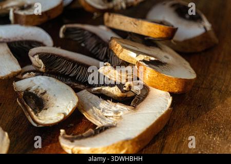 Detaillierte Nahaufnahme von frisch geschnittenen braunen Champignonpilzen auf einem hölzernen Schneidebrett. Stockfoto