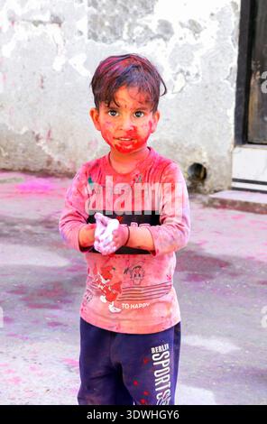 Hansi, Haryana, 14. März 20225: Nicht identifiziertes indisches Kleinkind mit Gesicht bedeckt mit rotem Pulver während der Holi-Festivalfeier in einem Bewohner Stockfoto