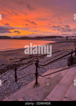 Llandudno North Shore, Wales, Stufen hinunter zum Strand, Sonnenaufgang, mit rotem Himmel, Küste Skyline in der Ferne Roter Himmel am Morgen, Seemann nehmen Warnung Stockfoto