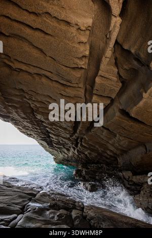 Im Inneren des atemberaubenden und großen Natursteinbogens am Meer im Paros Park auf der Insel Paros in Griechenland. Felsige geologische Landschaft und natürliche Attraktion. Stockfoto