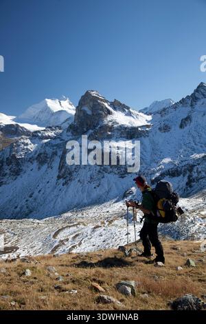 Backpacker mit einem großen Paket auf dem Wanderweg der Haute Route, der in Richtung Gruben in der Schweiz absteigt. Stockfoto