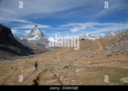 Wanderer auf einem Bergweg in Richtung Zermatt mit dem Matterhorn in der Ferne, Zermatt, Schweiz. Stockfoto