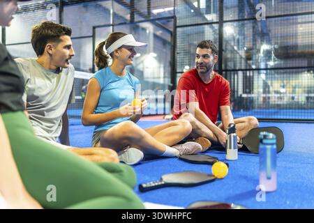 Eine Gruppe verschiedener Freunde, die sich auf dem blauen Pickleball-Platz entspannen und unterhalten, Paddel und Bälle halten, Freizeit und Cam genießen Stockfoto