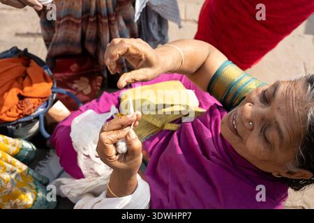 Eine ältere Frau in traditioneller Kleidung spinnt in Varanasi, Indien, Baumwollgarn von Hand und zeigt lokales Handwerk. Stockfoto