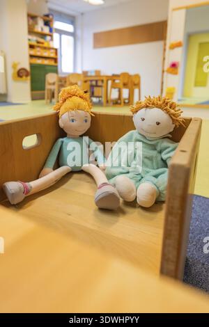 Zwei Puppen in einer Holzkiste, in einem kinderfreundlichen Zimmer mit farbenfroher Inneneinrichtung, Kindertagesstätte für Kleinkinder, Gechingen, Deutschland Stockfoto