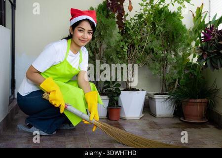 Professionelles asiatisches Reinigungsteam in festlichen Uniformen bietet weihnachtlichen Reinigungsservice, bereitet Haus und Büro auf die Feiertage vor. Stockfoto