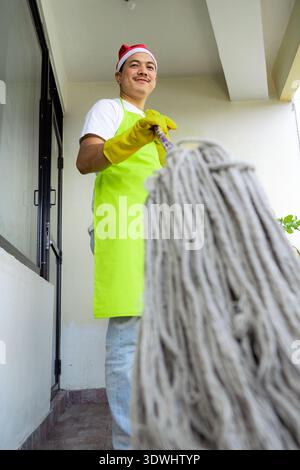 Professionelles asiatisches Reinigungsteam in festlichen Uniformen bietet weihnachtlichen Reinigungsservice, bereitet Haus und Büro auf die Feiertage vor. Stockfoto