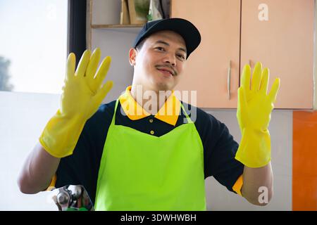 Professioneller männlicher Reiniger, der moderne Küche desinfiziert, Arbeitsplatten und Geräte abwischt Stockfoto