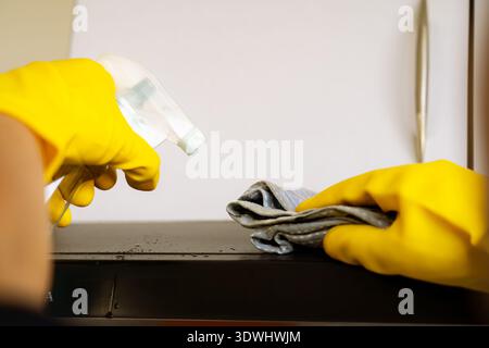 Professioneller männlicher Reiniger, der moderne Küche desinfiziert, Arbeitsplatten und Geräte abwischt Stockfoto