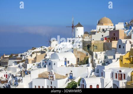 Griechenland. Santorini (Thira). Weiße Häuser und Windmühlen an einem Berghang im Dorf Oia Stockfoto