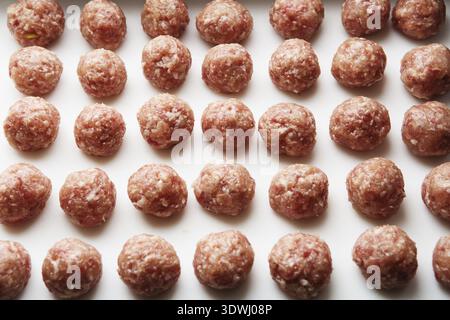 Frisch gekochte rohe Fleischbällchen liegen auf einem weißen Plastikbrett Stockfoto