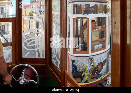 Zwei Standseilbahnen, die sich auf einer steilen Straße vorbeifahren, wobei der Fahrer im Fenster sichtbar ist, Lissabon, Lisboa, Portugal, Europa. Stockfoto